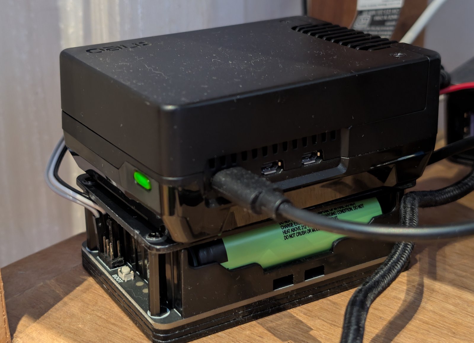Waveshare UPS Module 3S sitting under a Raspberry Pi 5, batteries visible through the base, green power LED lit